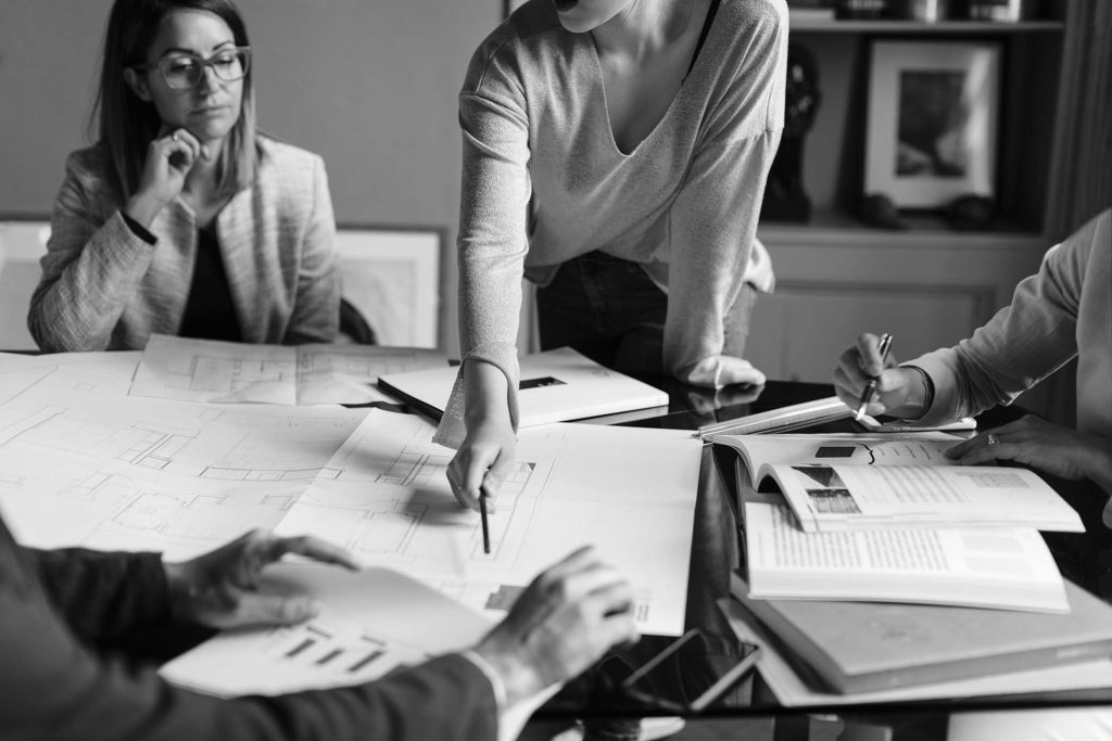 Two people reviewing architectural floor plans and kitchen layout drawings at a table
