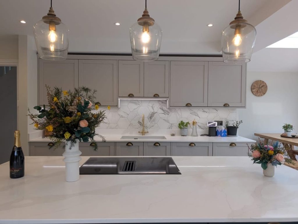 Grey shaker kitchen with marble hexagon tiling, brass fittings and glass pendant lights