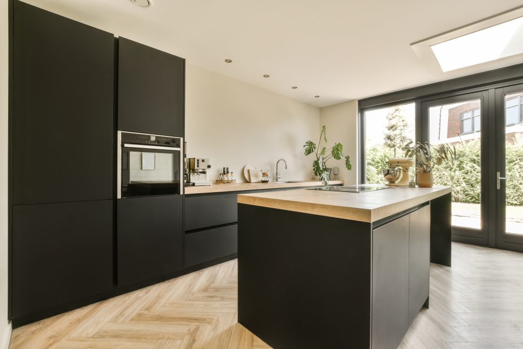 Black handleless kitchen with central island, oak worktop and herringbone wood flooring